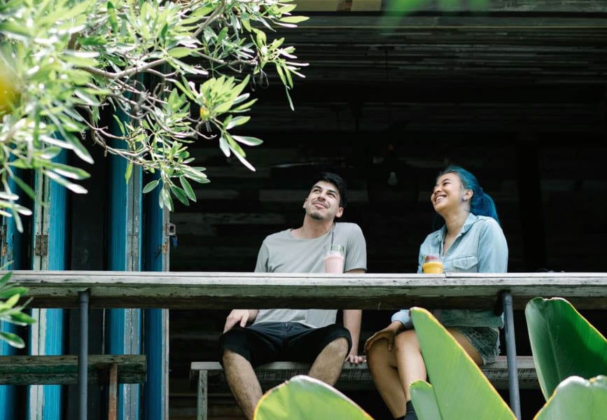 “A couple relaxes on a rustic patio surrounded by greenery, showcasing the benefits of eco-friendly landscaping tips.